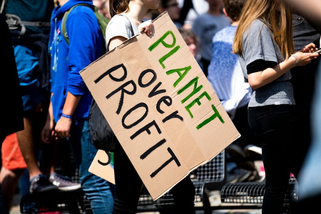 Youth climate protest with participants holding 'Planet Over Profit' sign.