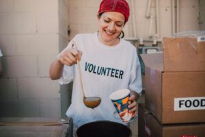 A cheerful volunteer serving food at a donation center, symbolizing generosity and community support.